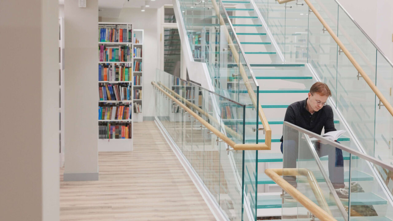 man in library is reading book sitting on steps of 2025 02 21 10 06 58 utc 1920x1080 1